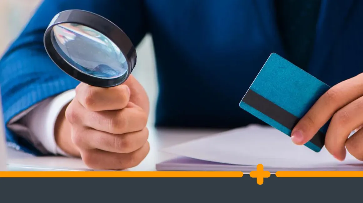 Mężczyzna w garniturze trzymający lupę i kartę kredytową