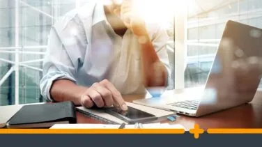 Biznesmen przy biurku korzystający ze smartfona i laptopa